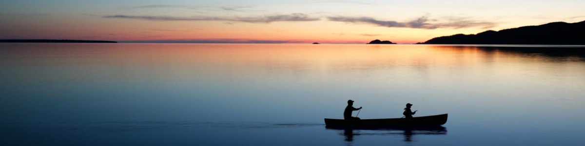 man and boy in canoe at sunset