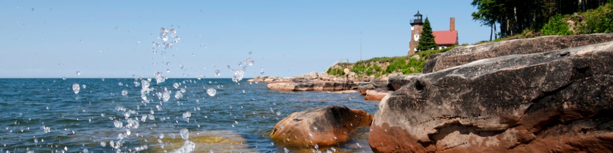 water on rocks by lighthouse